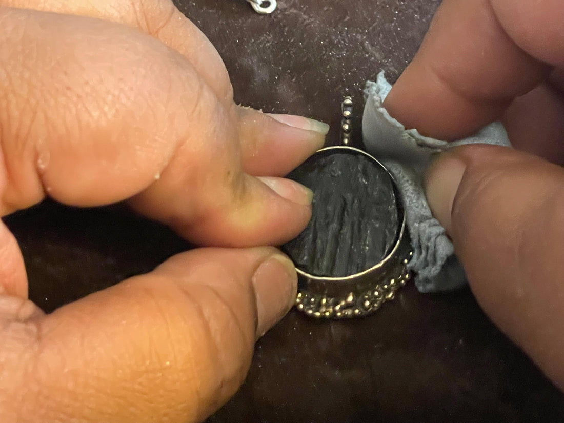 jewelry polishing cloth being used to polish a bronze textured pendant