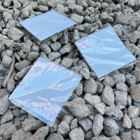 picture of 3 jewelry polishing cloths laying on river stones